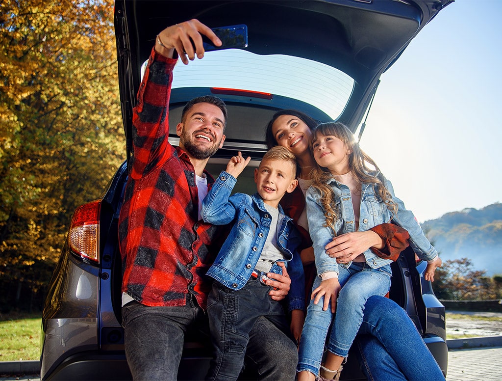 Conócenos 7 - familia haciendose una foto en el asiento trasero de su vehiculo